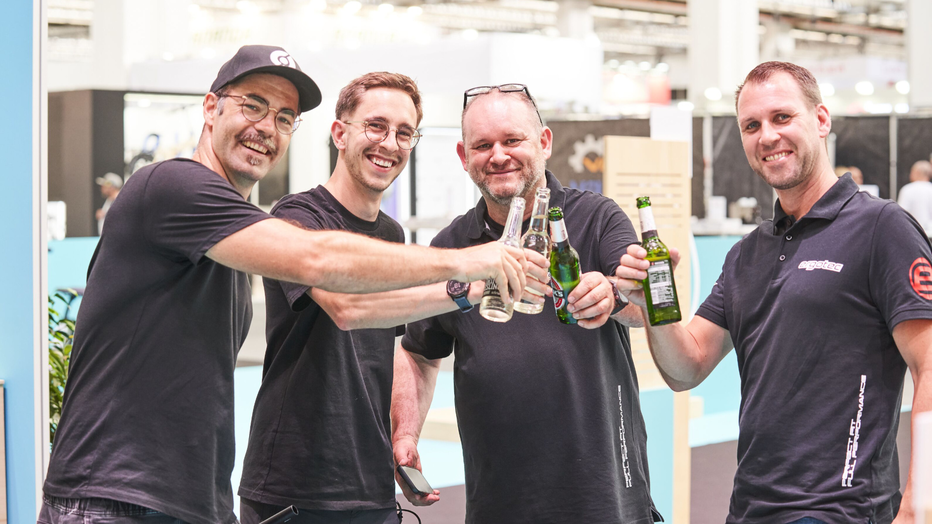 Four men clinking drinks together and celebrating at the trade fair.