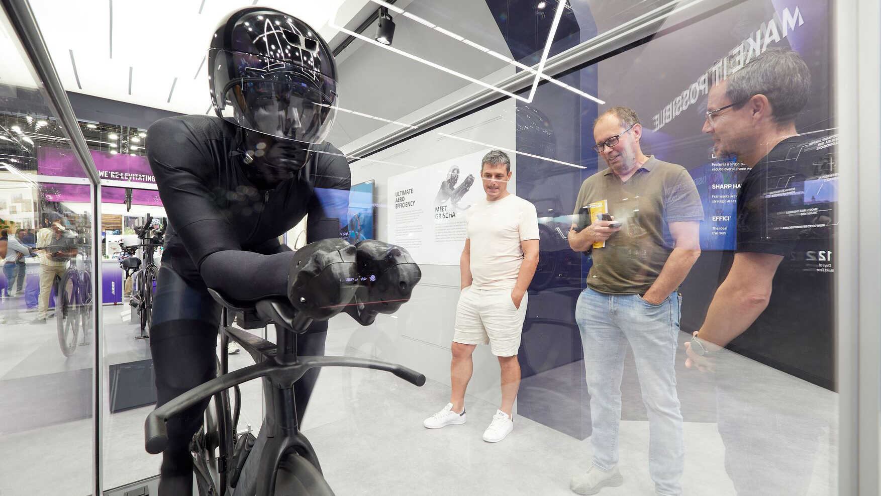 Visitors observing a futuristic bicycle concept with an aerodynamic riding position at an exhibition booth.