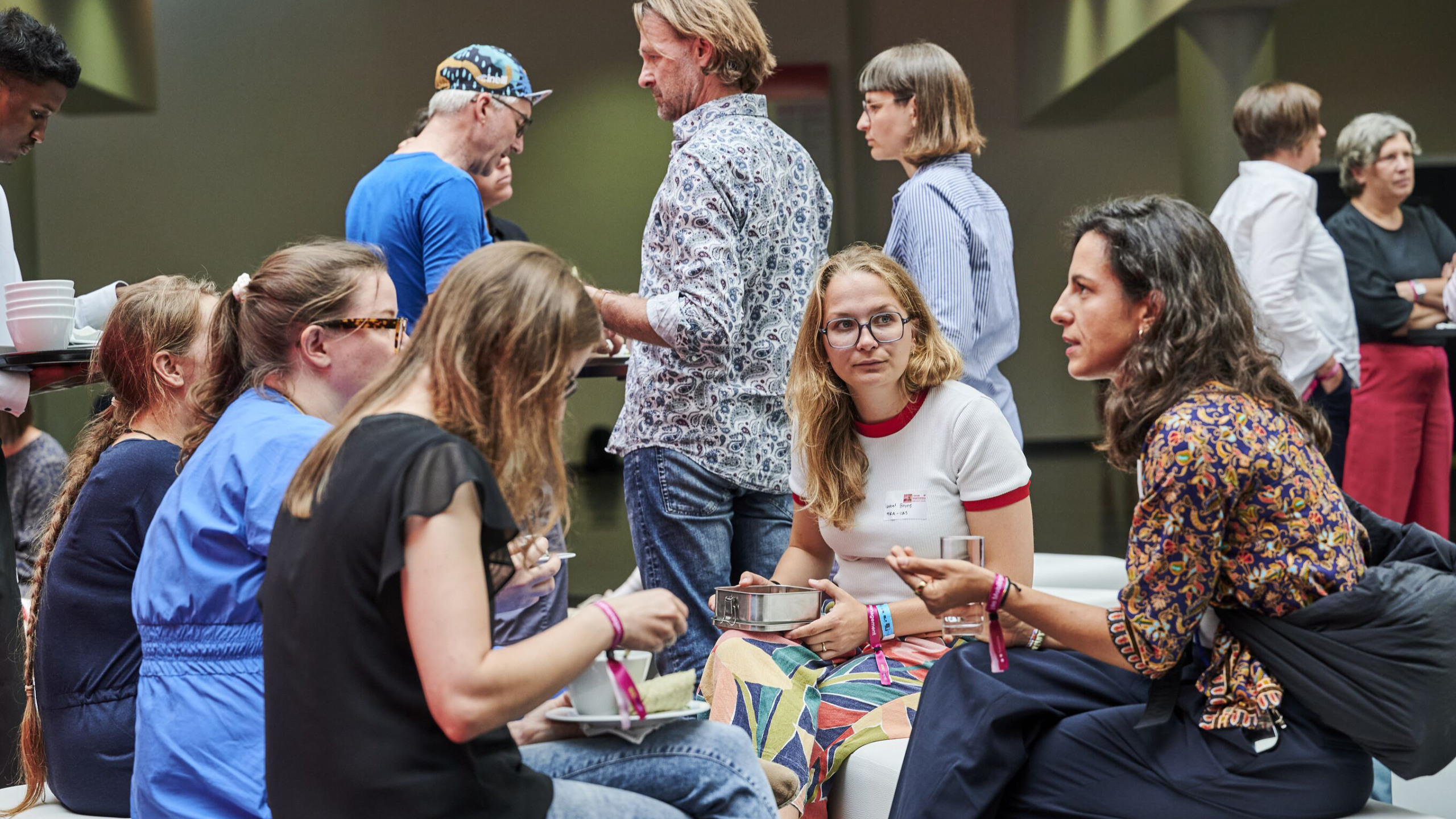 Participants sit together in small groups and chat in a relaxed atmosphere