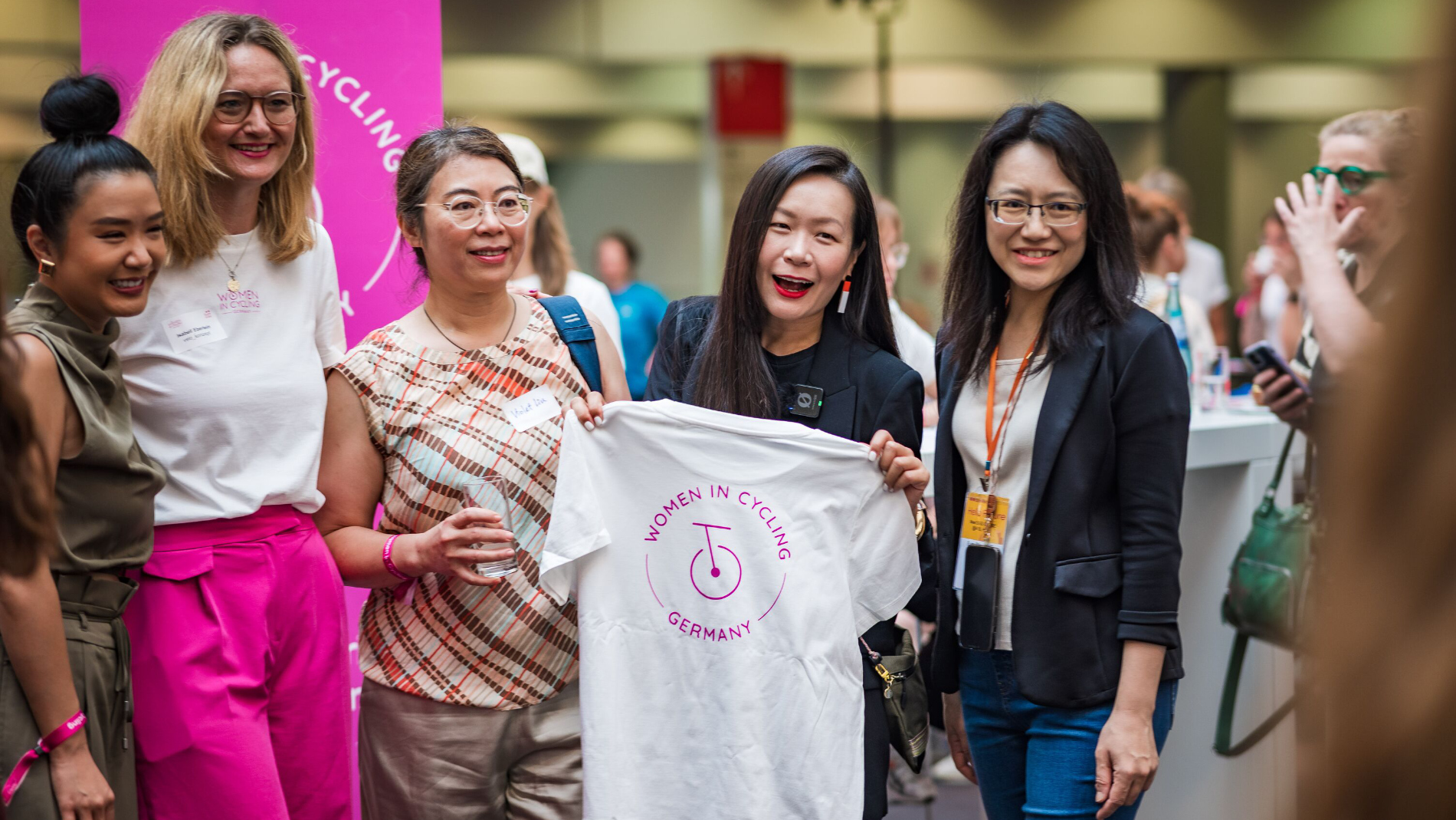 Group of participants presenting a “Women in Cycling Germany” T-shirt at a networking event.