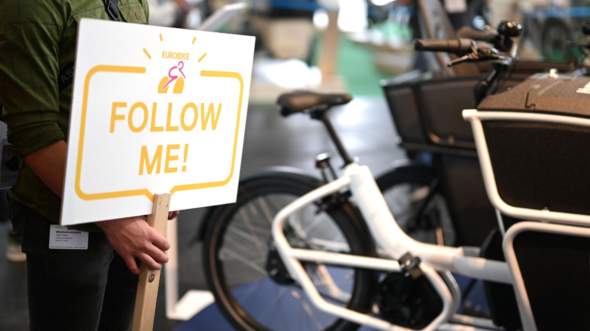 “Follow Me!” sign beside cargo bike at trade fair