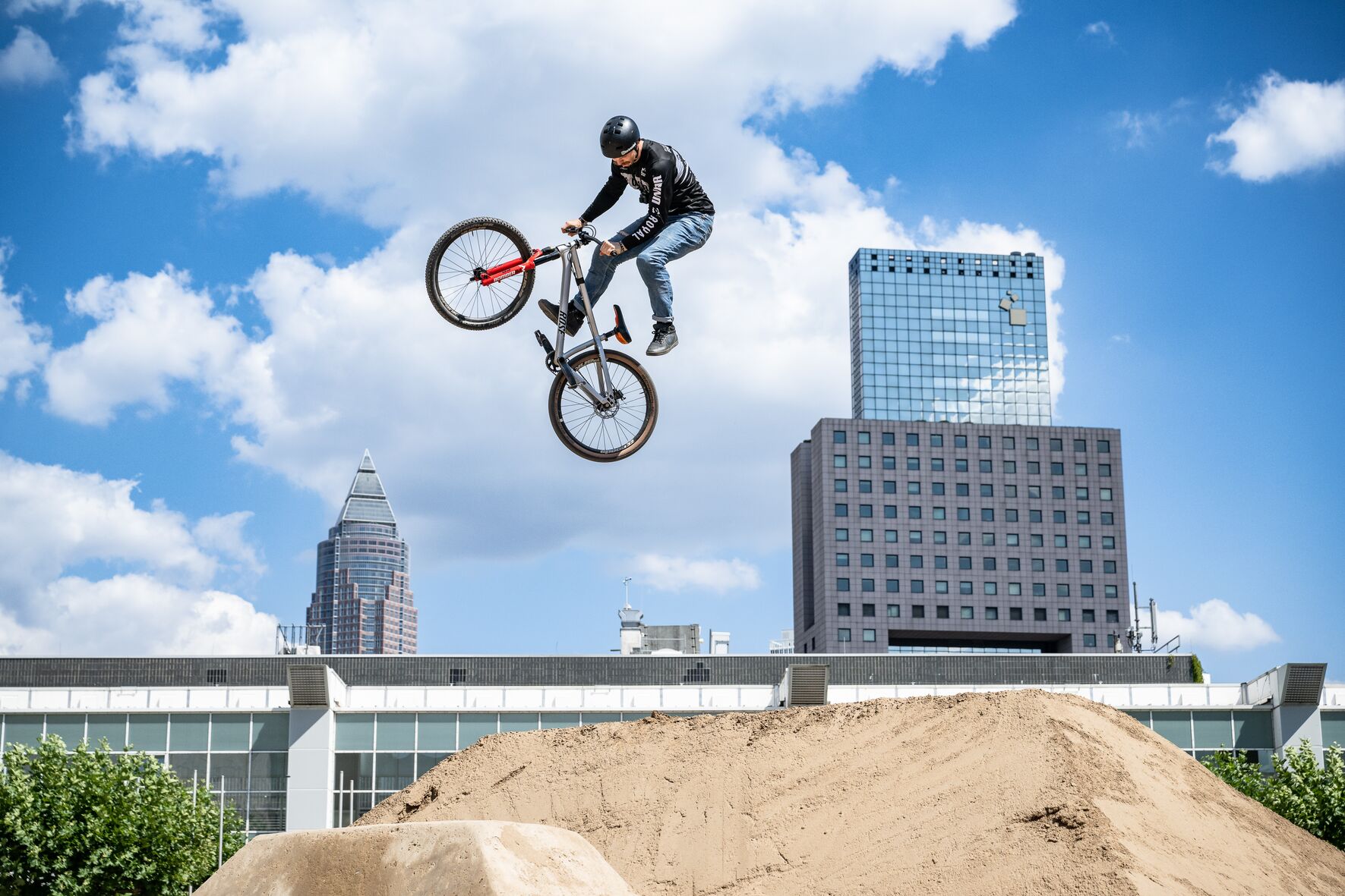 Ein Fahradfahrer springt mehrere Meter in der Luft. Im Hintergrund ist die Skyline Frankfurts zu sehen.